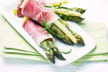 Green and white asparagus wrapped in prosciutto ham - obrazy, fototapety, plakaty
