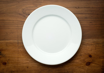 Empty white plate on wooden table