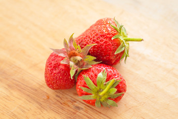 three strawberries on wooden table