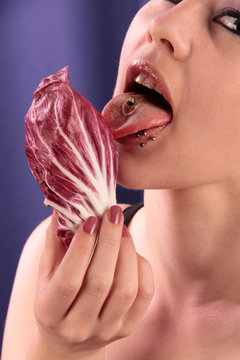 Eine nackte Frau leckt mit Zunge an Radicchio