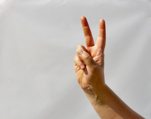 man hand shows victory sign closeup against white
