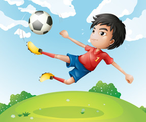 A football player in his red uniform kicking the ball