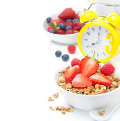 breakfast with granola, berries, yellow alarm clock isolated