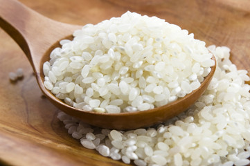 Rice in wooden spoon on kitchen table