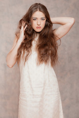 Fototapeta premium Sensual fashion woman with long hair. Wearing beige dress. Marbl