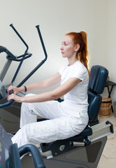 Young sports woman in sport center on velosimulator