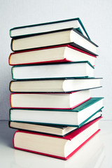 Stack of books on white reflective surface