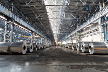 Rows of rolls of aluminum lie in production shop of plant.