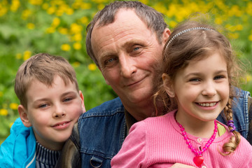 Fototapeta premium Grandfather, granddaughter and grandson smiling in nature.