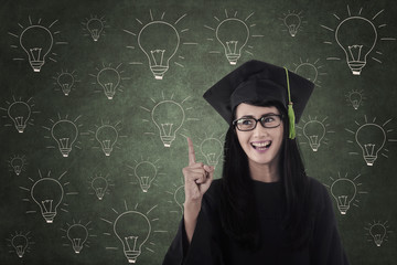 Happy student graduate in front of light bulbs drawing