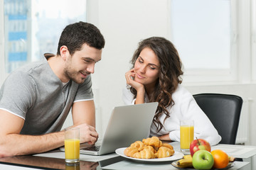 Obraz na płótnie Canvas beautiful couple having breakfast with a laptop