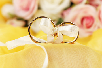 Wedding rings tied with ribbon on bright background