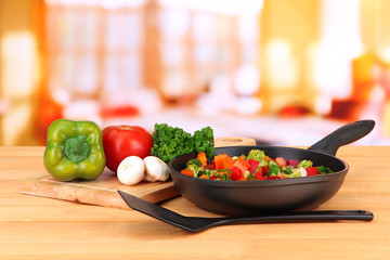 Vegetable ragout in pan,  on wooden table on bright background