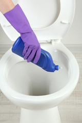 Woman hand with spray bottle cleaning a toilet bowl in a