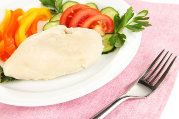 Boiled chicken breast on plate with vegetables close up