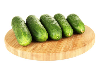 Tasty green cucumbers on wooden cutting board, isolated on