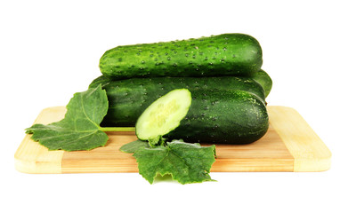 Tasty green cucumbers on wooden cutting board, isolated on