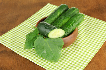 Tasty green cucumbers on color napkin, on wooden background