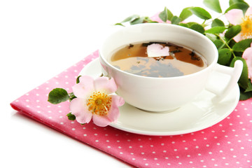 Cup of herbal tea with hip rose flowers, isolated on white