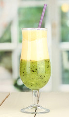 Delicious fruit smoothie on wooden table on window background