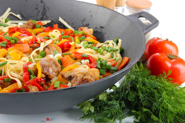 Noodles with vegetables on wok close-up