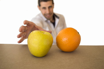 man decides to take an apple which is next to an orange