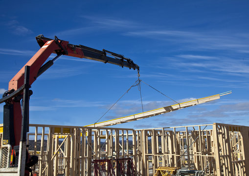 Crane lifts trusses onto new houses under construction