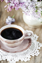 Cup of coffee and lilac flowers bouquet