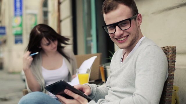 Happy young male student with tablet computer in cafe