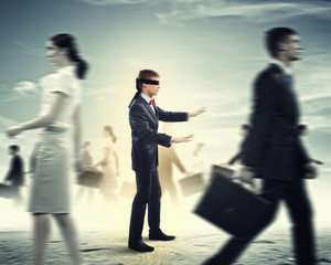 Businessman in blindfold among group of people