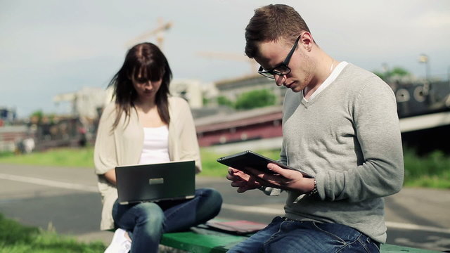 Young students with tablet and laptop in the city