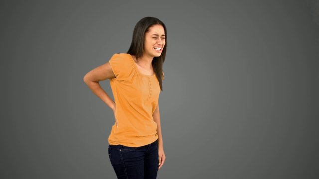 Woman rubbing painful back on grey background