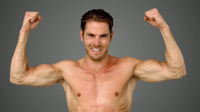 Sportsman raising his arms on grey background