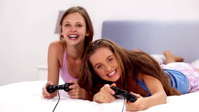 Excited girls playing video games on bed