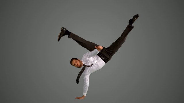 Businessman doing one hand handstand on grey background