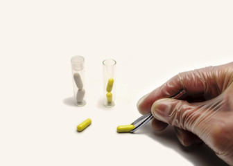 manipulating scientific pills with tweezers white background