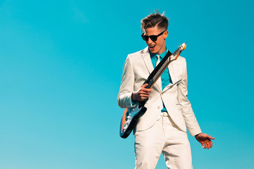 Retro fifties male electric guitar player wearing white suit and
