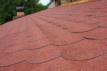 Red asphalt shingle roofing on a roof and chimney