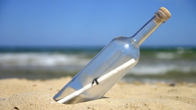 Bottle with a letter on sand on the beach