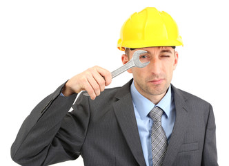 Young businessman in helmet with wrench isolated on white.