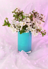 Flowering branches in vase on light fabric background