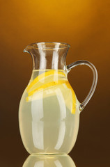 Lemonade in pitcher on orange background