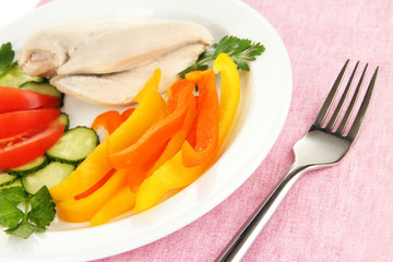 Boiled chicken breast on plate with vegetables close up
