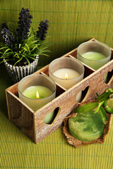 Obraz na płótnie Canvas Candles in wooden candlestick, lavender and soap, on green mat