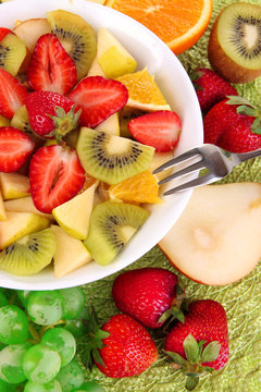 Useful fruit salad of fresh fruits and berries in bowl close-up