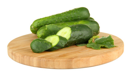 Tasty green cucumbers on wooden cutting board, isolated on