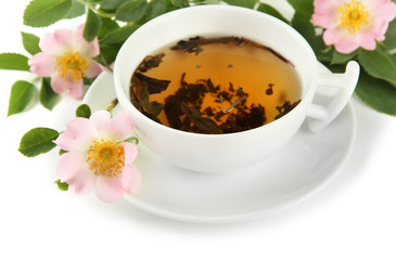 Cup of herbal tea with hip rose flowers, isolated on white