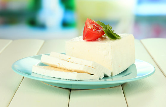 Sheep milk cheese, with basil and tomato on bright background