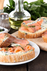 Fish sandwiches on cutting board and plate on wooden table