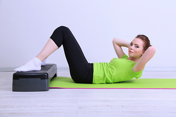 Beautiful young woman exercises on stepper